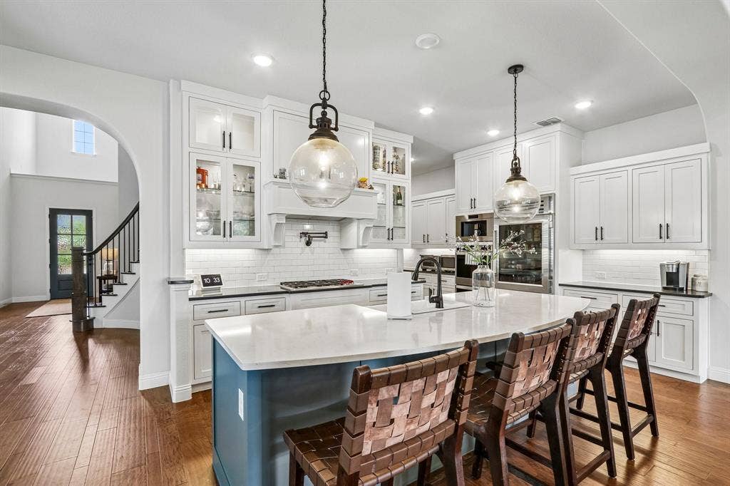 1657 Lilac Lane, Celina, TX 75009 Gourmet kitchen with white cabinetry, a large center island with seating, built-in stainless steel appliances, and wood-finish flooring