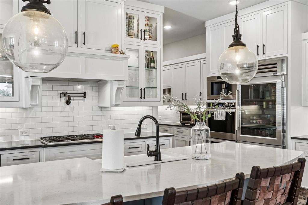 1657 Lilac Lane, Celina, TX 75009 White shaker-style cabinetry with glass-front accents, subway tile backsplash, built-in stainless steel appliances, and a kitchen island with an undermount sink