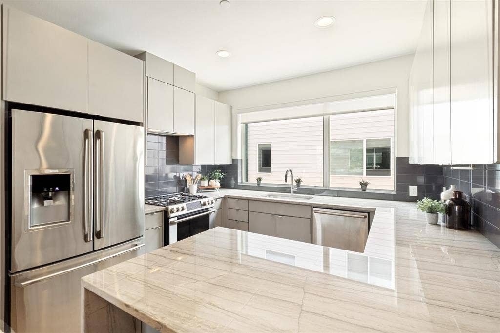 1430 Grigsby Avenue, #104, Dallas, TX 75204 Quartz countertops, stainless steel appliances(refrigerator included), gas range. Clean and modern. Breakfast bar for stools.