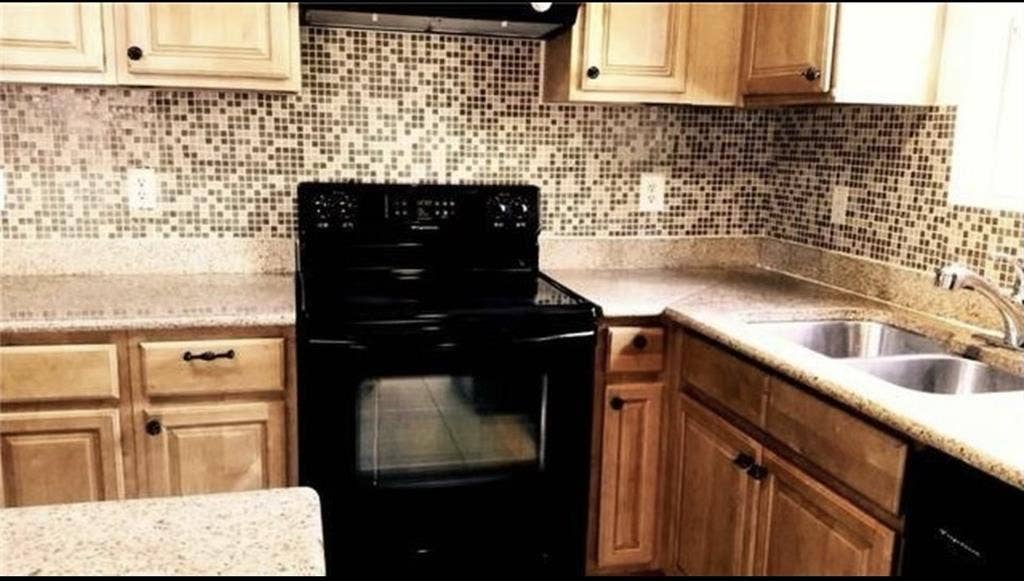 3713 Pearl Trail, Garland, TX 75044 Kitchen featuring natural wood cabinetry, mosaic tile backsplash, solid surface countertops, a black range, and a double basin stainless steel sink