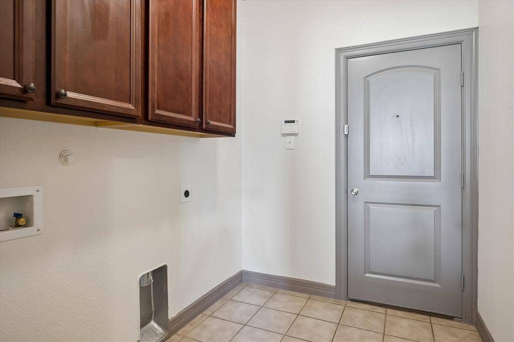 Foyer with ceramic tile flooring, rich wood-finish cabinetry, and a gray-painted interior door featuring a two-panel design