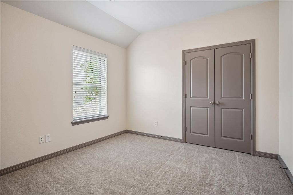 Vaulted ceiling accentuates the neutral color palette with carpet flooring and window blinds