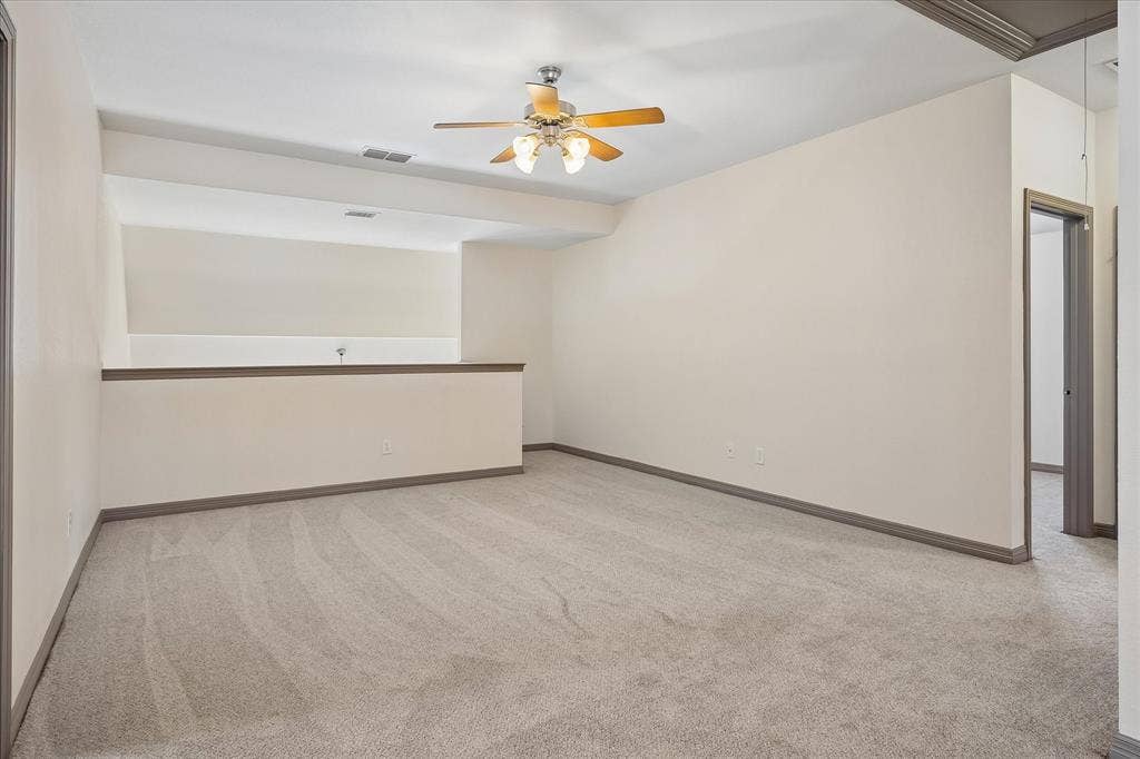 Spacious open floor plan with neutral carpet flooring, recessed ceiling lights, and a ceiling fan