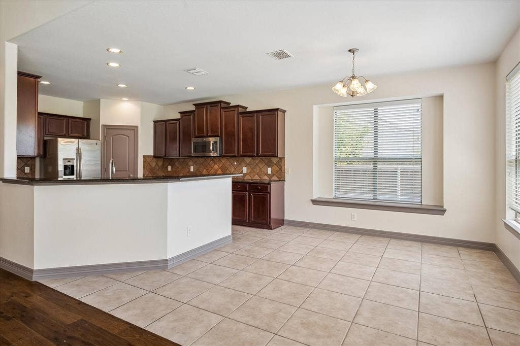 Kitchen featuring dark wood cabinetry, stainless steel appliances, and a tiled backsplash
