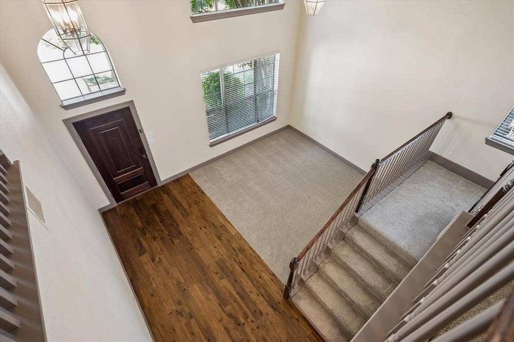 Two-story foyer with wood-finish flooring, arched window with transom, and a carpeted staircase with wood railing