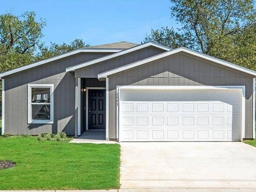1005 Dawson Street, Waco, TX 76704 Gray siding exterior with white trim, a dark paneled front door, a single-car garage, and a concrete driveway