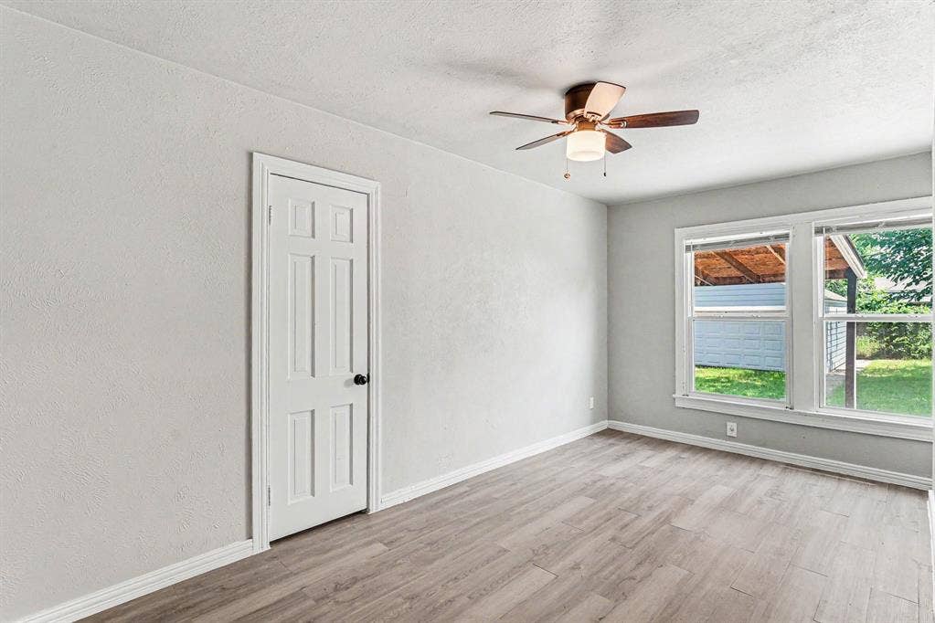 1108 E Robert Street, Fort Worth, TX 76104 Wood-finish flooring, white trim, multi-pane windows, ceiling fan with light fixture, and six-panel interior door