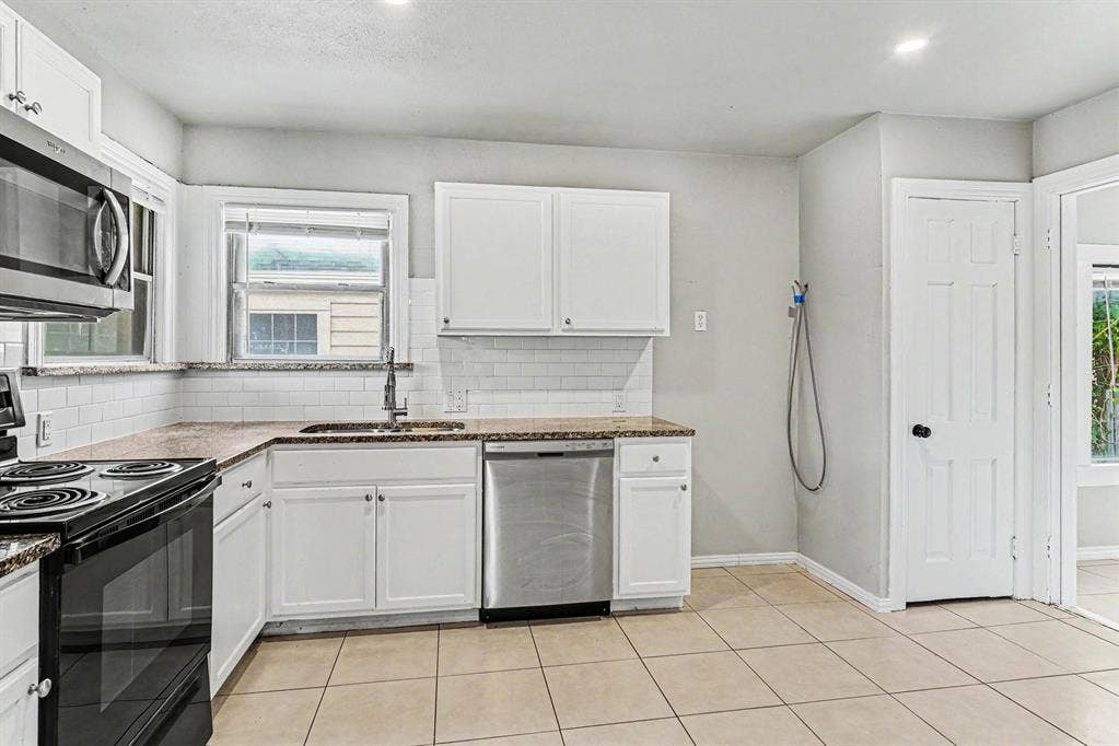 1108 E Robert Street, Fort Worth, TX 76104 White cabinetry, tile flooring, subway tile backsplash, stainless steel appliances, and recessed lighting