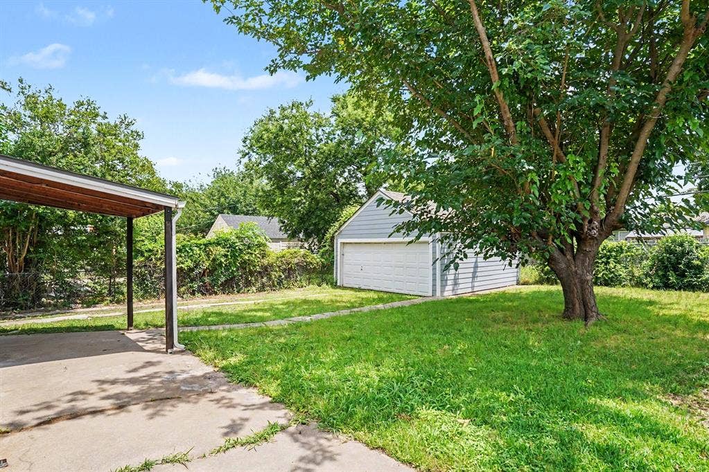 1108 E Robert Street, Fort Worth, TX 76104 Expansive grassy yard with mature trees, detached garage, and a covered carport
