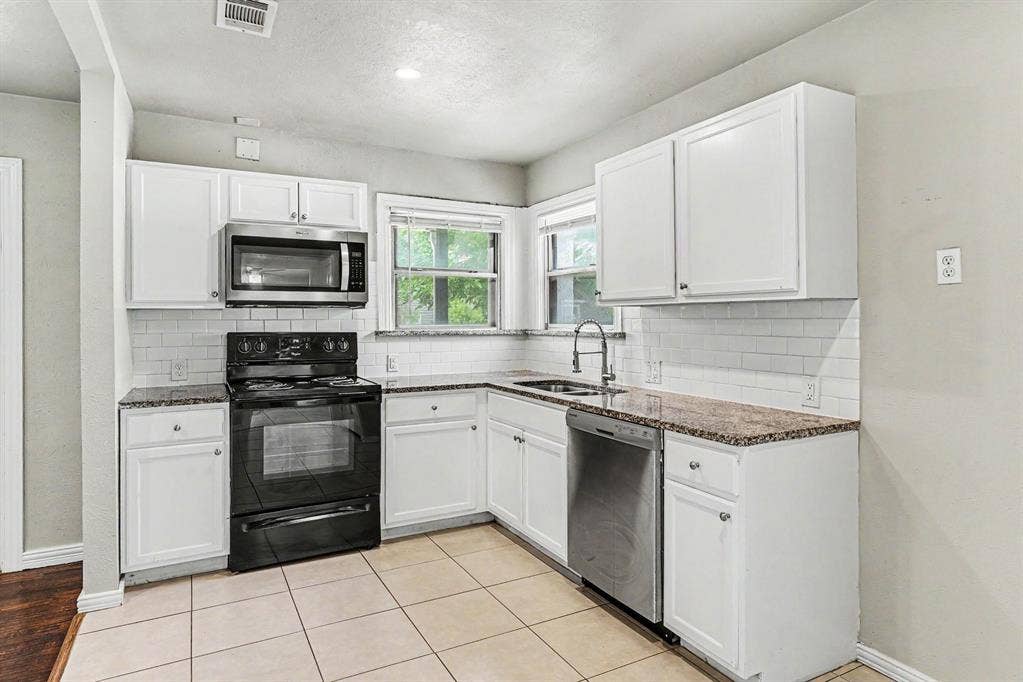 1108 E Robert Street, Fort Worth, TX 76104 Kitchen featuring white cabinetry, stone-finish countertops, subway tile backsplash, stainless steel appliances, and tile flooring