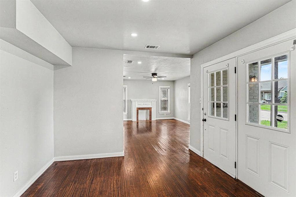 1108 E Robert Street, Fort Worth, TX 76104 Wood-finish flooring throughout, white interior walls, recessed lighting, double entry doors with glass panels, and a decorative fireplace with a mantel