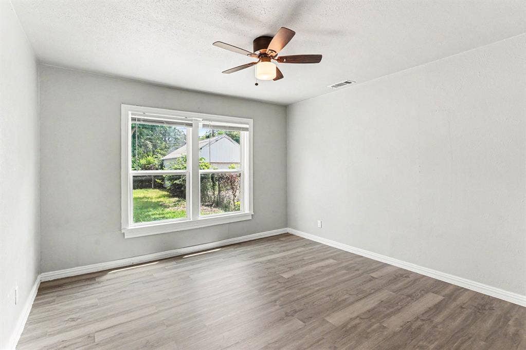 1108 E Robert Street, Fort Worth, TX 76104 Light gray wall paint, wood-finish flooring, white trim, and a ceiling fan with integrated lighting