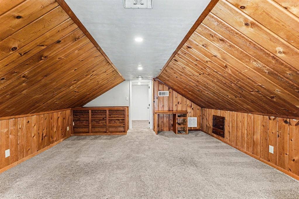 1108 E Robert Street, Fort Worth, TX 76104 Sloped wood-paneled ceilings, built-in shelving, built-in desk, wood-paneled walls, and carpeted flooring