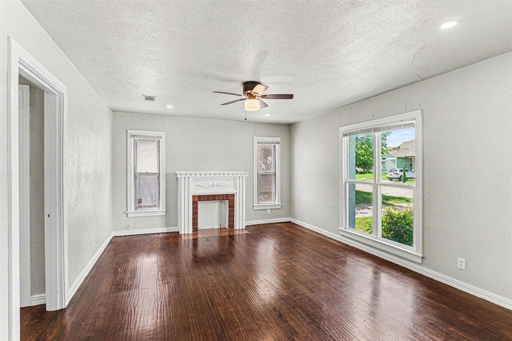 1108 E Robert Street, Fort Worth, TX 76104 Spacious living area featuring rich wood-finish flooring, a decorative fireplace with a white mantel, an overhead ceiling fan, and recessed lighting