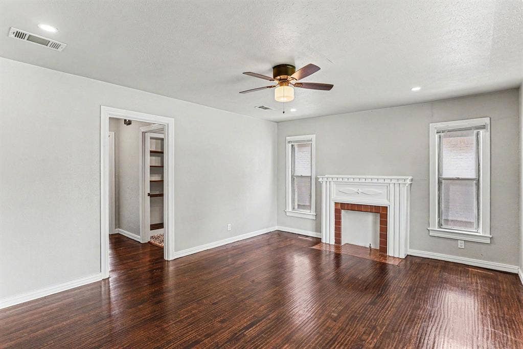 1108 E Robert Street, Fort Worth, TX 76104 Rich wood-finish flooring, a decorative fireplace with a brick surround, and two windows with white trim