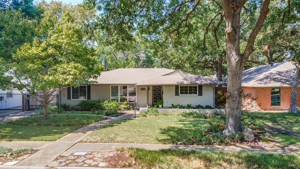 6719 Braeburn Drive, Dallas, TX 75214 Ranch-style exterior with a light-toned facade, dark window shutters, and a well-maintained lawn