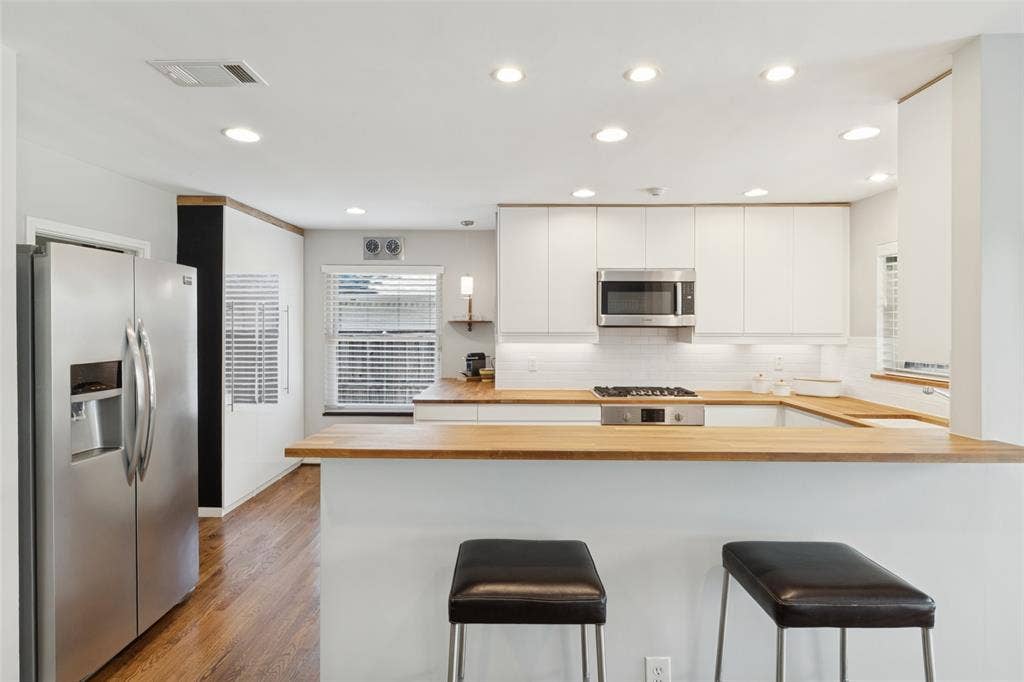 6719 Braeburn Drive, Dallas, TX 75214 Kitchen featuring white cabinetry, light wood countertops, stainless steel appliances, wood-finish flooring, and recessed lighting