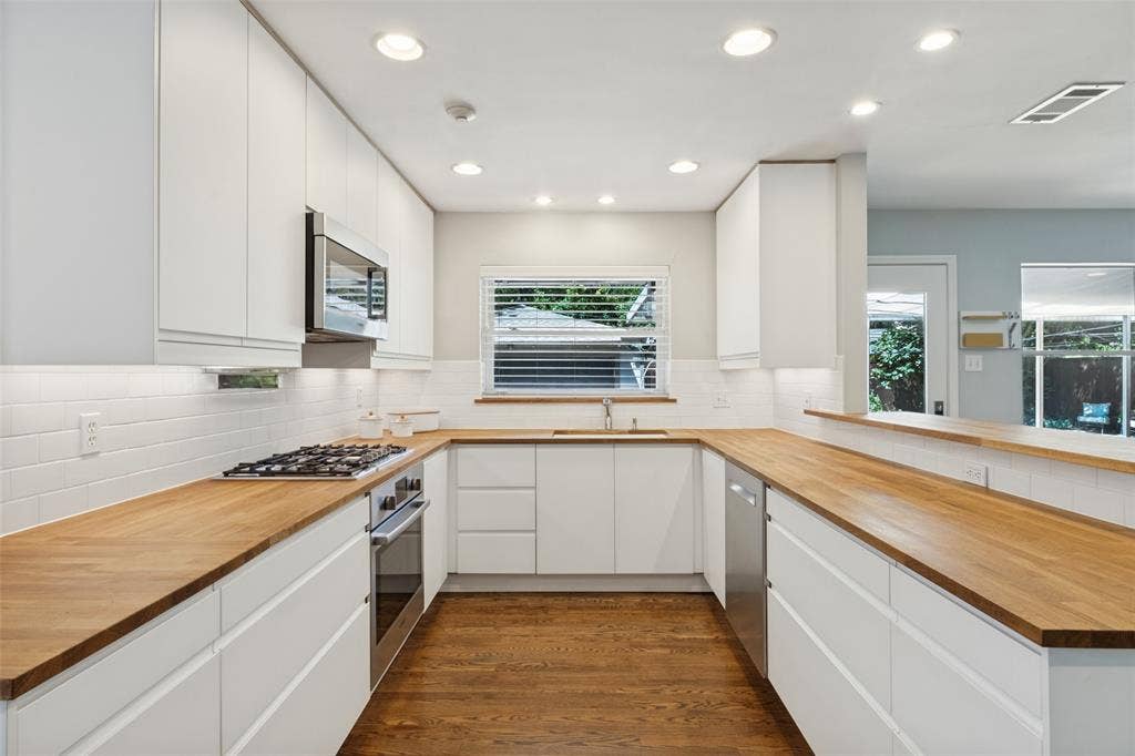 6719 Braeburn Drive, Dallas, TX 75214 Kitchen featuring wood-finish countertops, white flat-panel cabinetry, stainless steel appliances, a subway tile backsplash, and recessed lighting