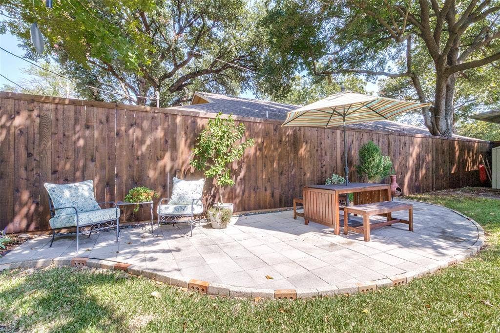 6719 Braeburn Drive, Dallas, TX 75214 Paved stone patio area with a brick border, surrounded by a wood privacy fence