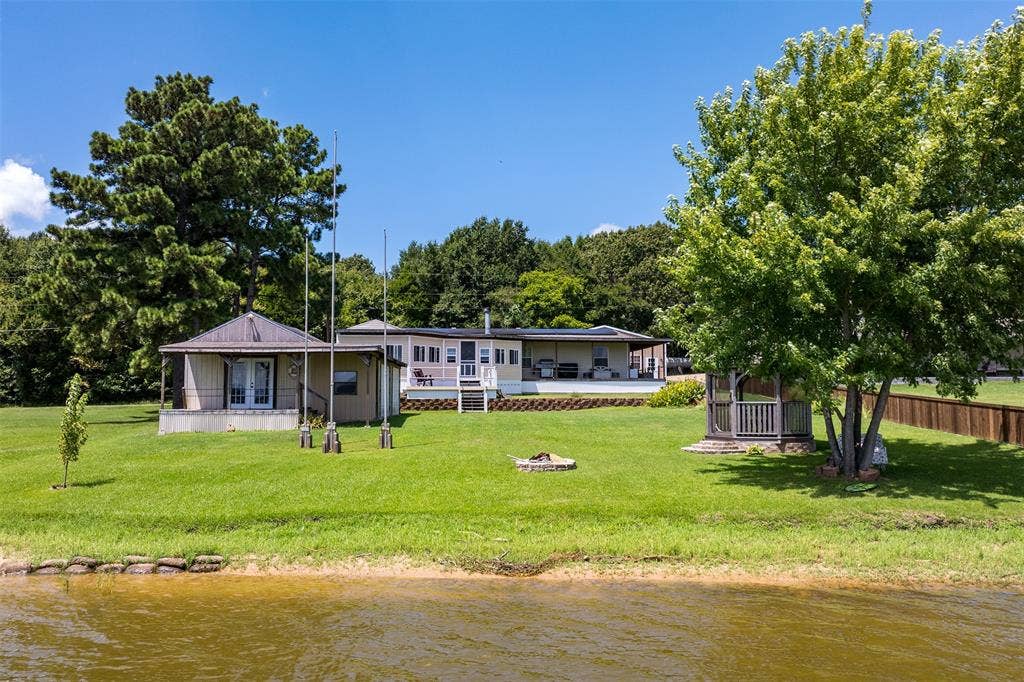 Back of home with large storage shed with deck looking out to water.