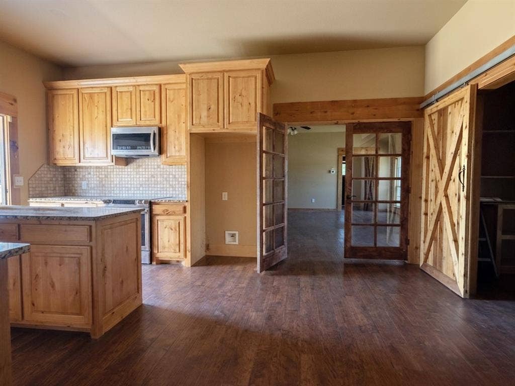 Kitchen featuring wood-finish cabinetry, stone countertops, and tile backsplash