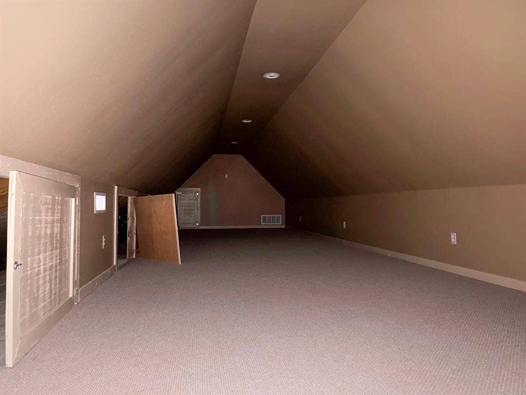 Expansive carpeted area with sloped ceilings and recessed lighting