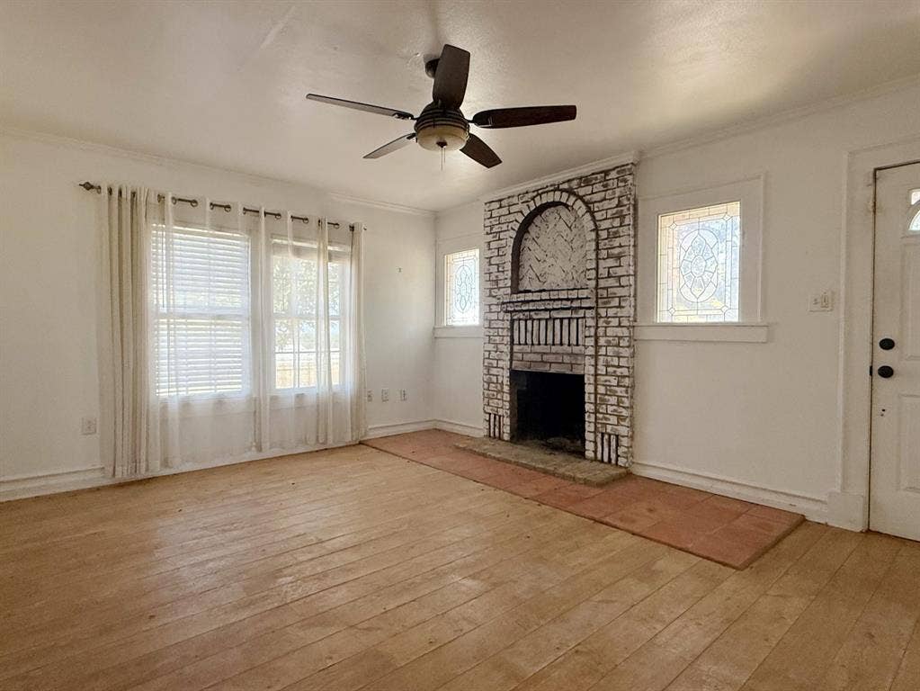 Brick fireplace feature with an arched alcove, wood-finish flooring, and decorative stained-glass windows