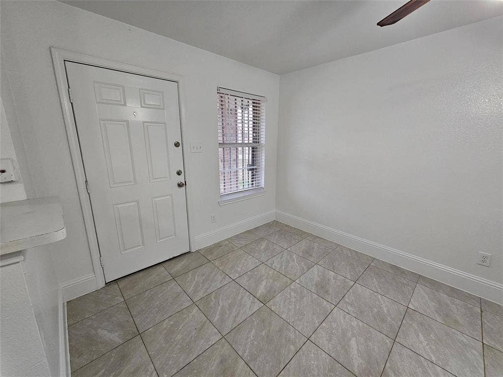 1615 Herald Street, #1613, Dallas, TX 75215 White paneled door, window with blinds, wood-finish ceiling fan, neutral tile flooring, and white baseboards