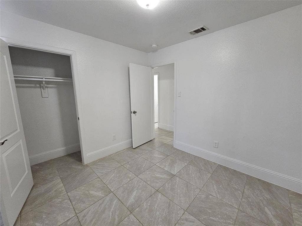 1615 Herald Street, #1613, Dallas, TX 75215 Square tile flooring, white walls, recessed ceiling light, and a built-in closet with hanging rod