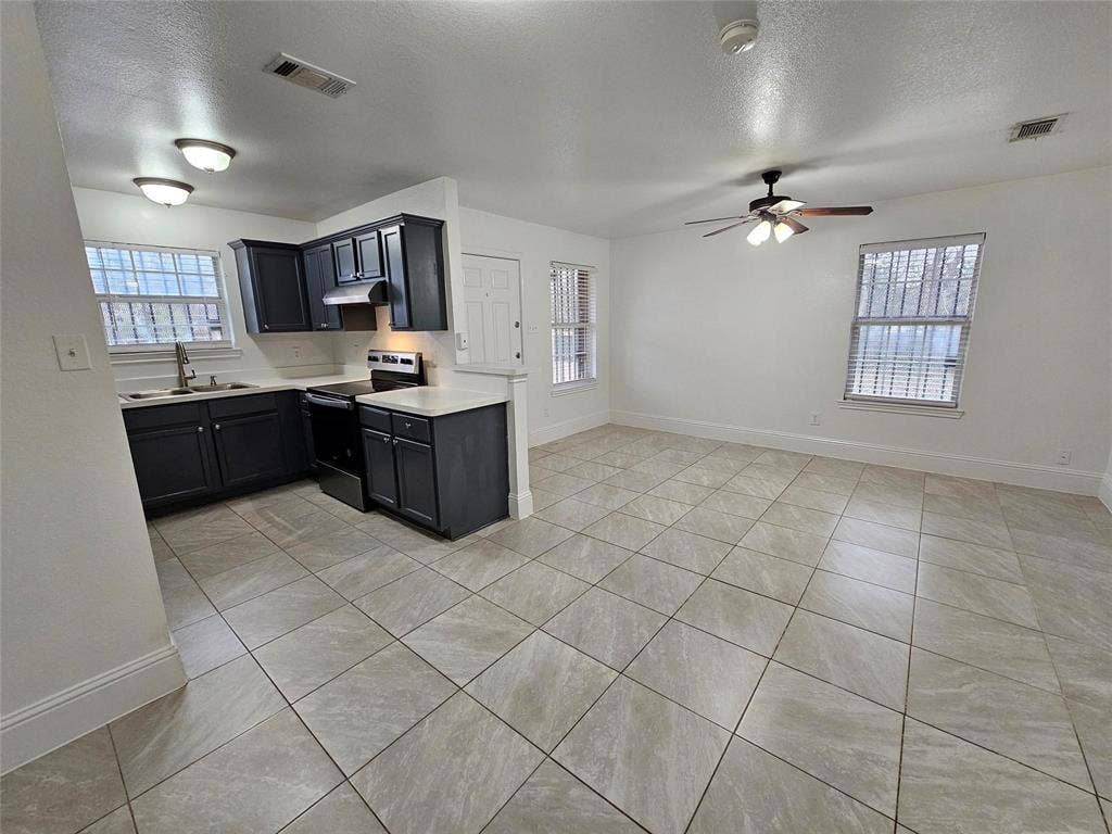 1615 Herald Street, #1613, Dallas, TX 75215 Open-concept living space with tile flooring, dark cabinetry, light countertops, and a ceiling fan