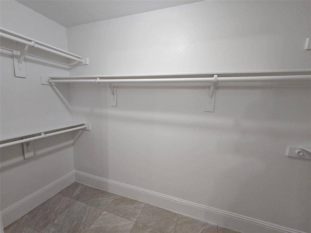 1615 Herald Street, #1613, Dallas, TX 75215 Walk-in closet with multiple white shelving units and hanging rods, complemented by light-toned tile flooring and white trim