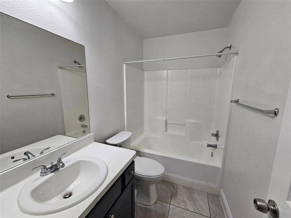 1615 Herald Street, #1613, Dallas, TX 75215 Bathroom with a vanity, oval sink, and a combination tub and shower with white tile surround