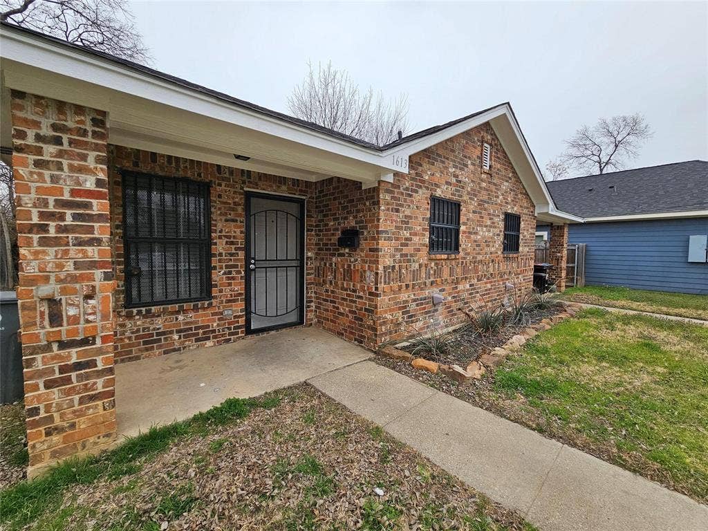 1615 Herald Street, #1613, Dallas, TX 75215 Brick exterior with a covered porch, front entry door with security screen, and a concrete walkway