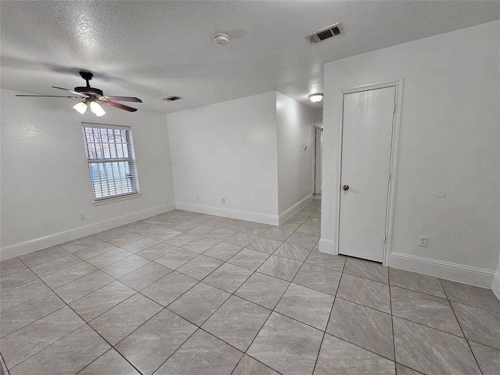 1615 Herald Street, #1613, Dallas, TX 75215 Spacious room featuring neutral tile flooring, window with horizontal blinds, and a ceiling fan with integrated lighting