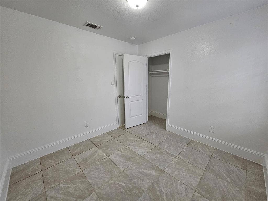 1615 Herald Street, #1613, Dallas, TX 75215 Neutral white wall finish, recessed lighting, tile flooring, interior door with polished hardware, and an integrated closet with hanging rod