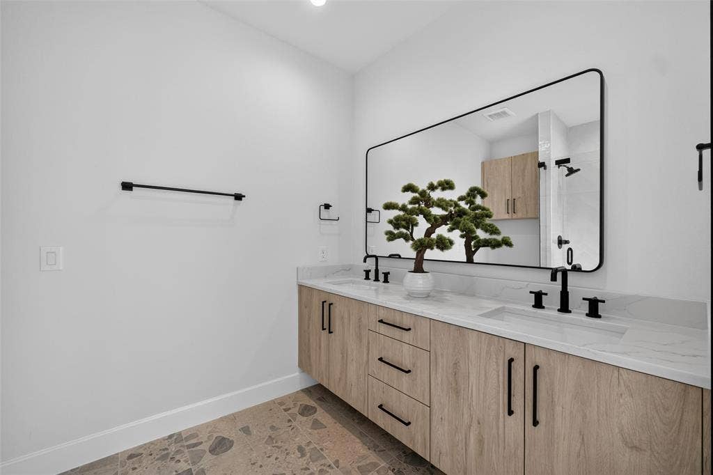 Dual vanity with light wood-finish cabinetry, white countertops, and matte black fixtures