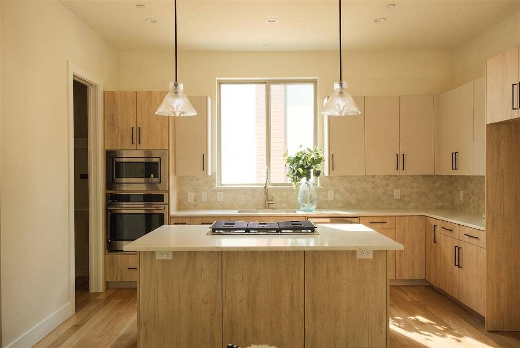 Kitchen featuring quartzite countertops, GE Cafe series appliances and Visual Comfort light fixtures