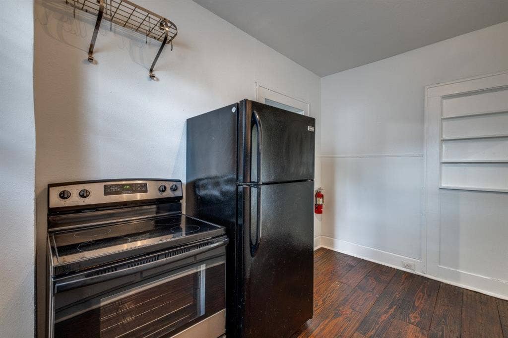 804 Sunset Avenue, #C, Dallas, TX 75208 Stainless steel electric range, black refrigerator, wood-finish flooring, and built-in shelving