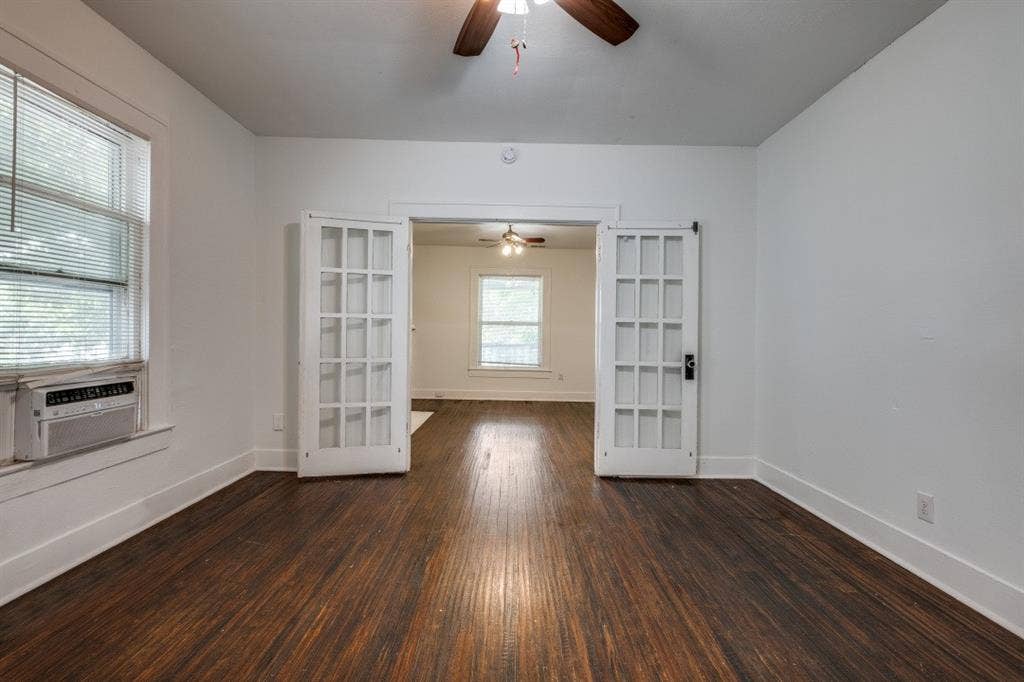804 Sunset Avenue, #C, Dallas, TX 75208 Hardwood flooring, white walls, double French doors, large window with blinds, and a ceiling fan