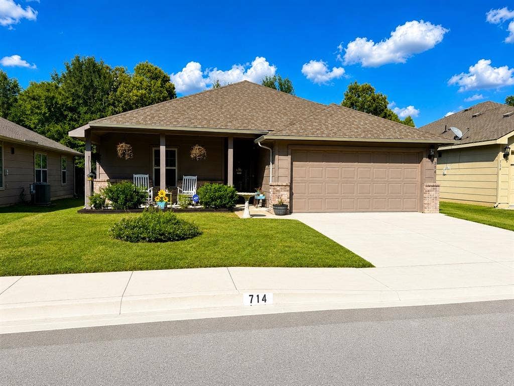 714 N Wofford Street, Athens, TX 75751 Single-story residence featuring a covered front porch, attached garage, concrete driveway, and established front landscaping