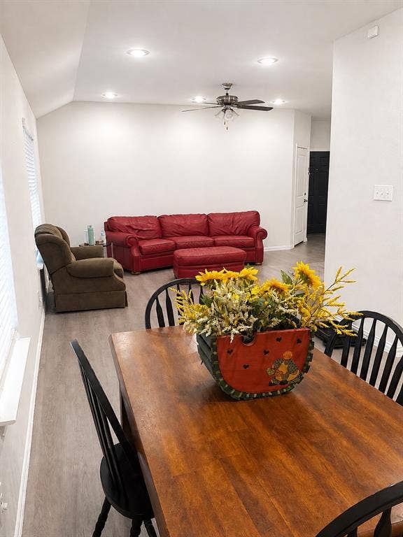 714 N Wofford Street, Athens, TX 75751 Open-concept living area featuring wood-finish dining table with seating for four, recessed ceiling lighting, ceiling fan with integrated light fixture, and direct sightlines to the adjoining living room with red upholstered sofa and brown upholstered armchair