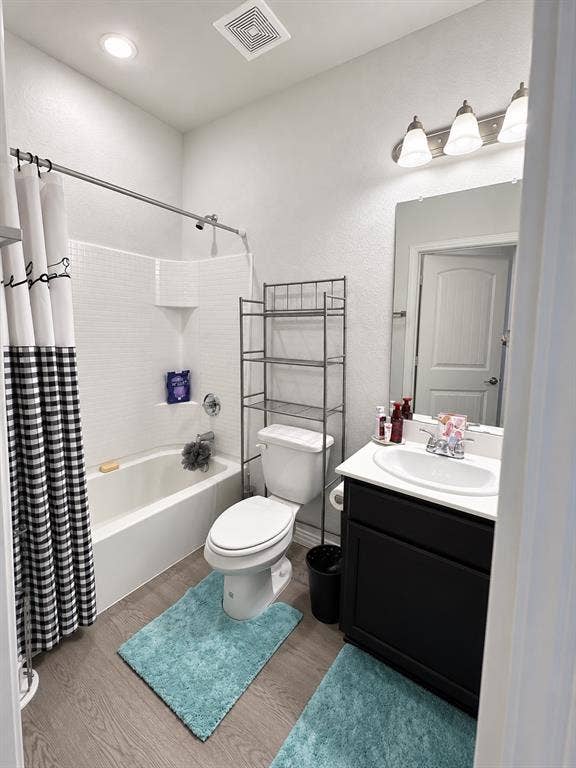714 N Wofford Street, Athens, TX 75751 Full bathroom featuring a tub-shower combination with subway tile surround, a single vanity with a dark cabinet base, a white countertop, and wood-finish flooring