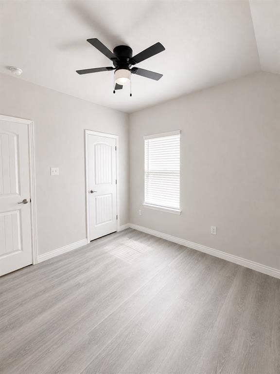 714 N Wofford Street, Athens, TX 75751 Vaulted ceiling featuring a ceiling fan with integrated lighting, two panel doors, a window with blinds, and wood-finish flooring