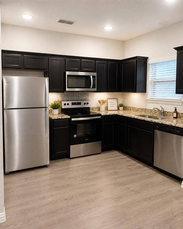 714 N Wofford Street, Athens, TX 75751 Kitchen featuring dark wood-finish cabinetry, stainless steel appliances, speckled countertops, wood-finish flooring, and recessed lighting