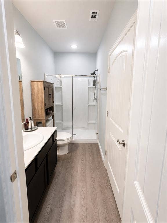 714 N Wofford Street, Athens, TX 75751 Bathroom featuring a single-sink vanity with dark cabinetry, wood-finish flooring, and a glass-enclosed shower