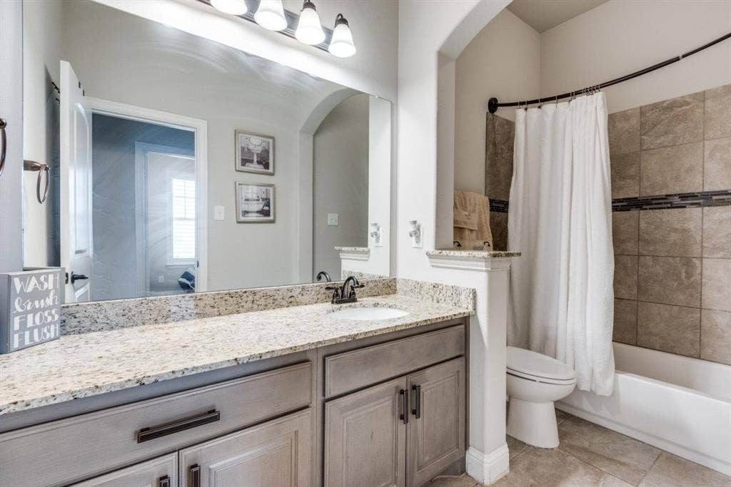 6911 Truth Drive, Dallas, TX 75236 Vanity with a granite countertop, undermount sink, and dark bronze faucet