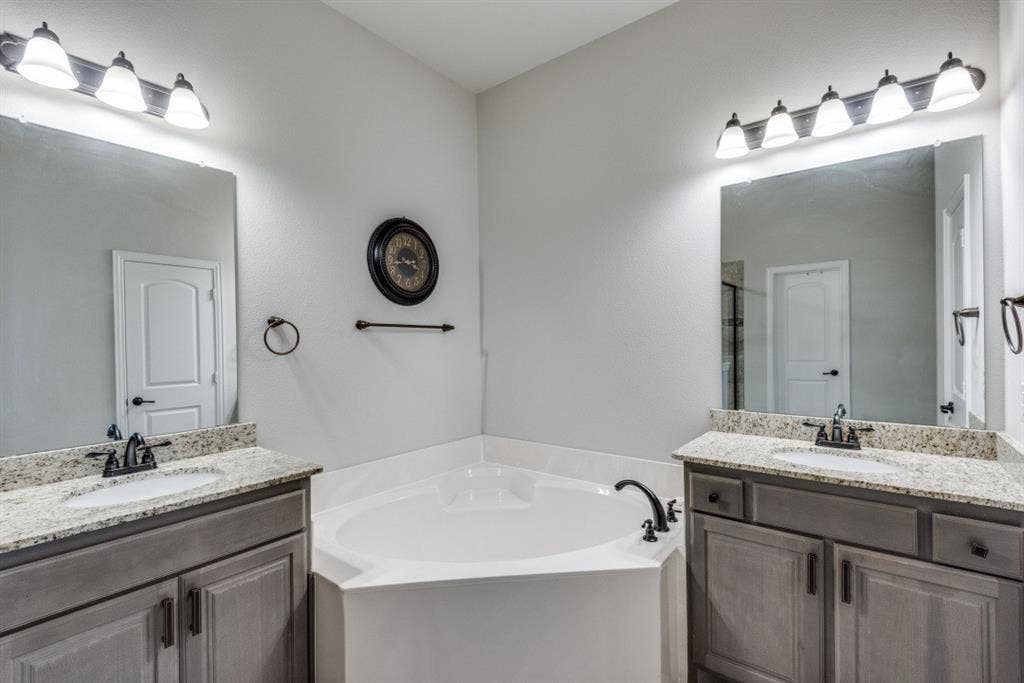 6911 Truth Drive, Dallas, TX 75236 Dual vanities with granite countertops, undermount sinks, and bronze-finish fixtures