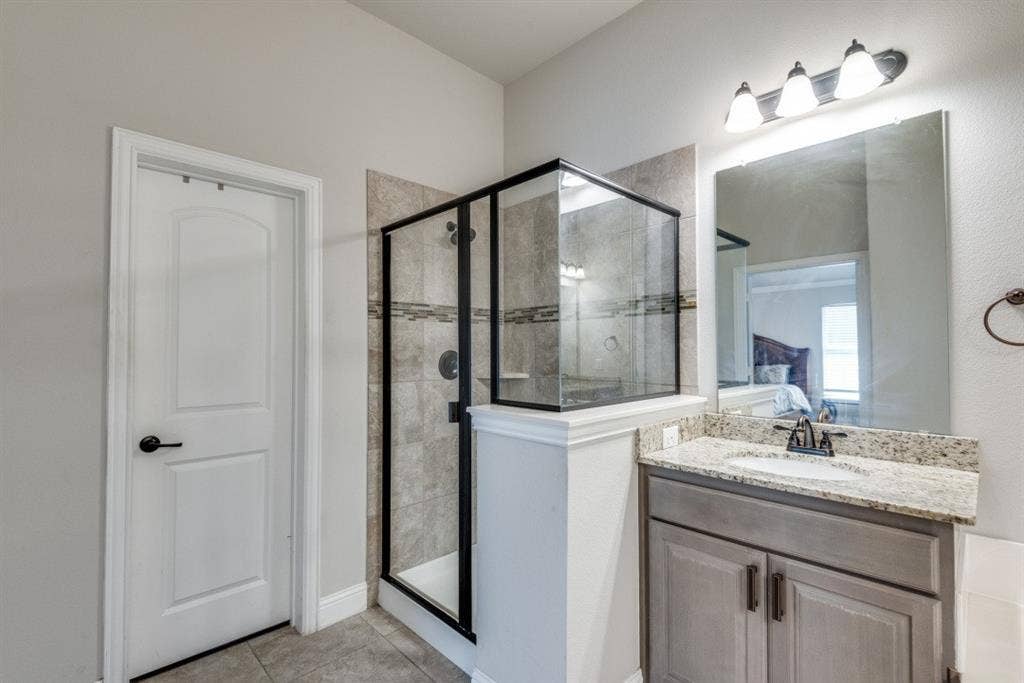 6911 Truth Drive, Dallas, TX 75236 Walk-in shower with tiled surround and glass enclosure
