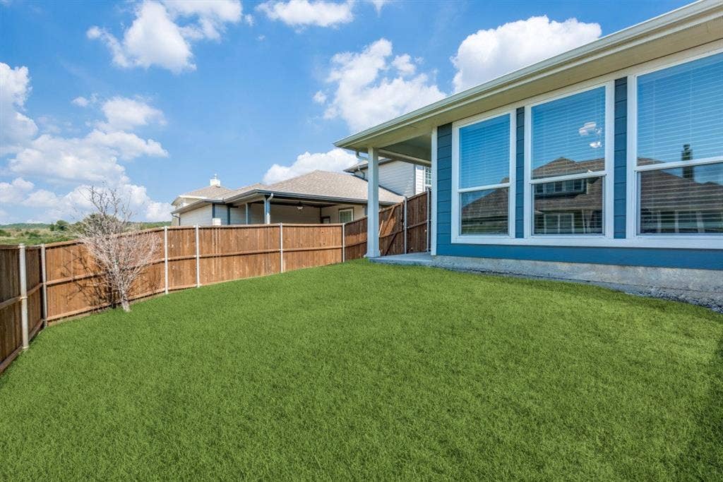 6911 Truth Drive, Dallas, TX 75236 Spacious backyard featuring a wood privacy fence, covered patio, and multiple large windows