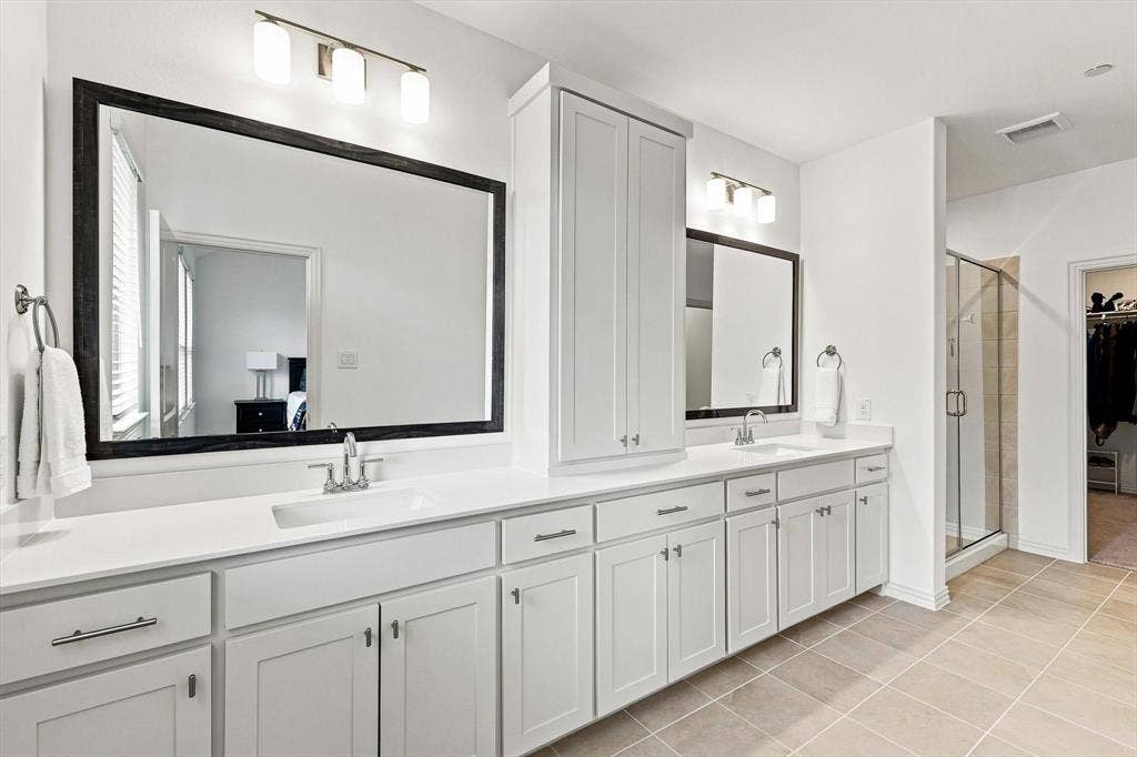 4833 Lunker Street, McKinney, TX 75071 Space to spread out and start the day right. An expansive dual-sink vanity, abundant cabinetry, and oversized mirrors bring both style and function to the primary bath.